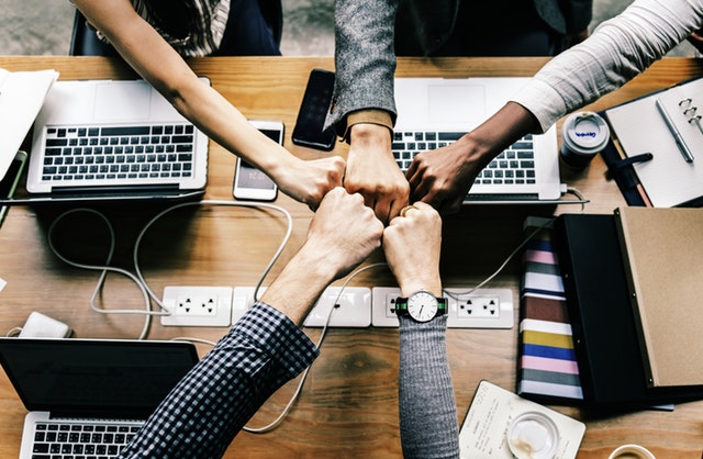 Group fist bump over laptops